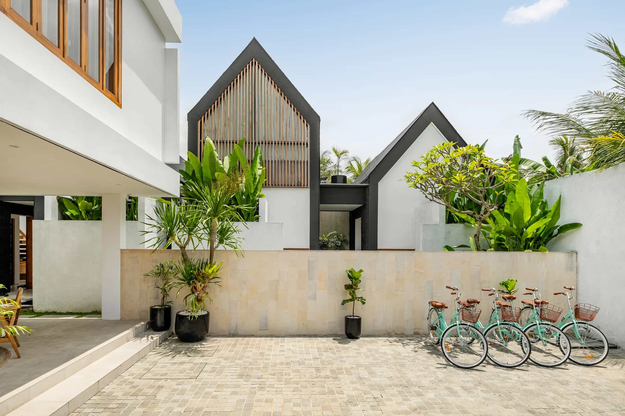 Tannari Villas arrival courtyard with both villas, tropical planting, and guest bicycles