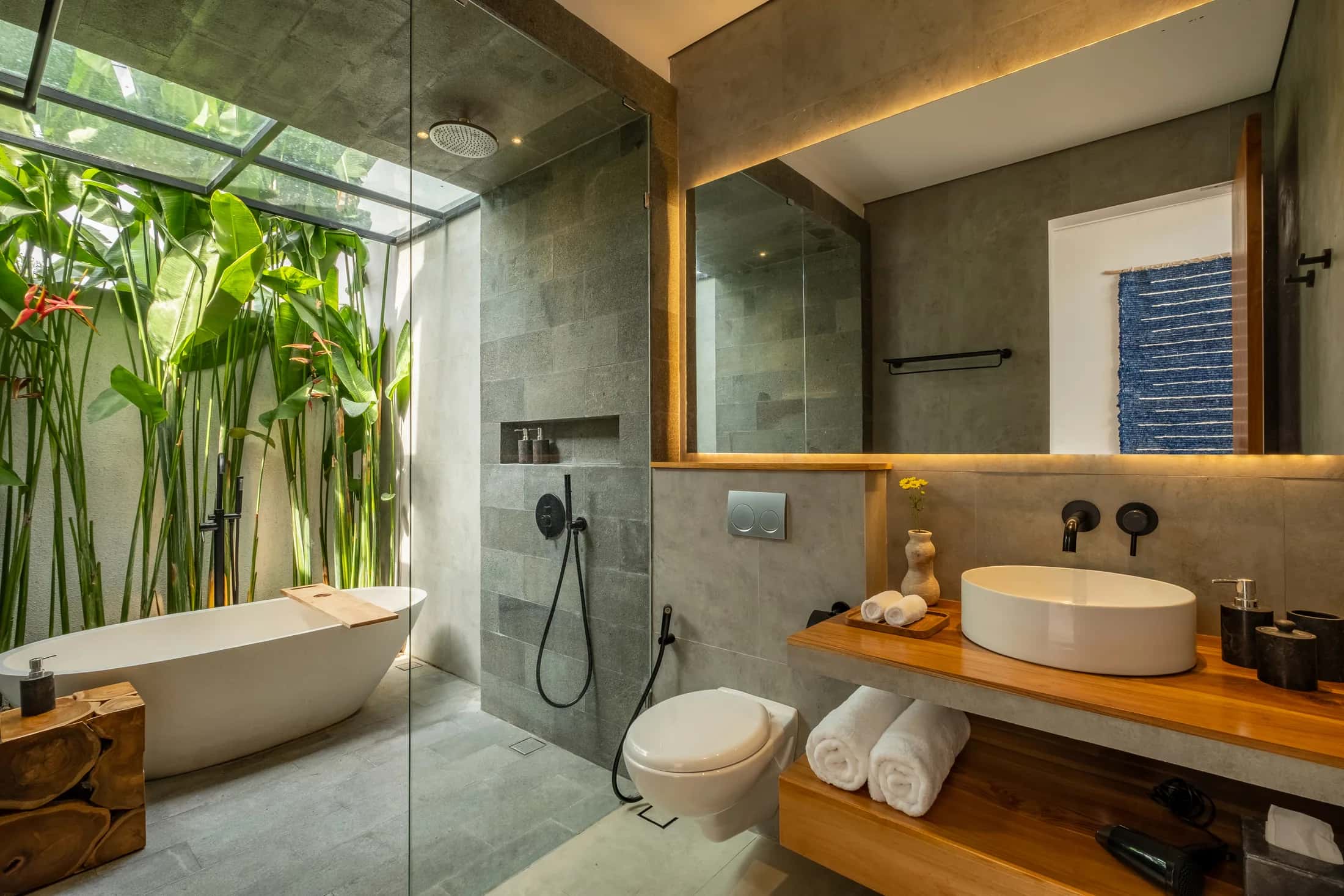 Mezzanine villa bathroom with bathtub, vanity, skylight, and tropical planting