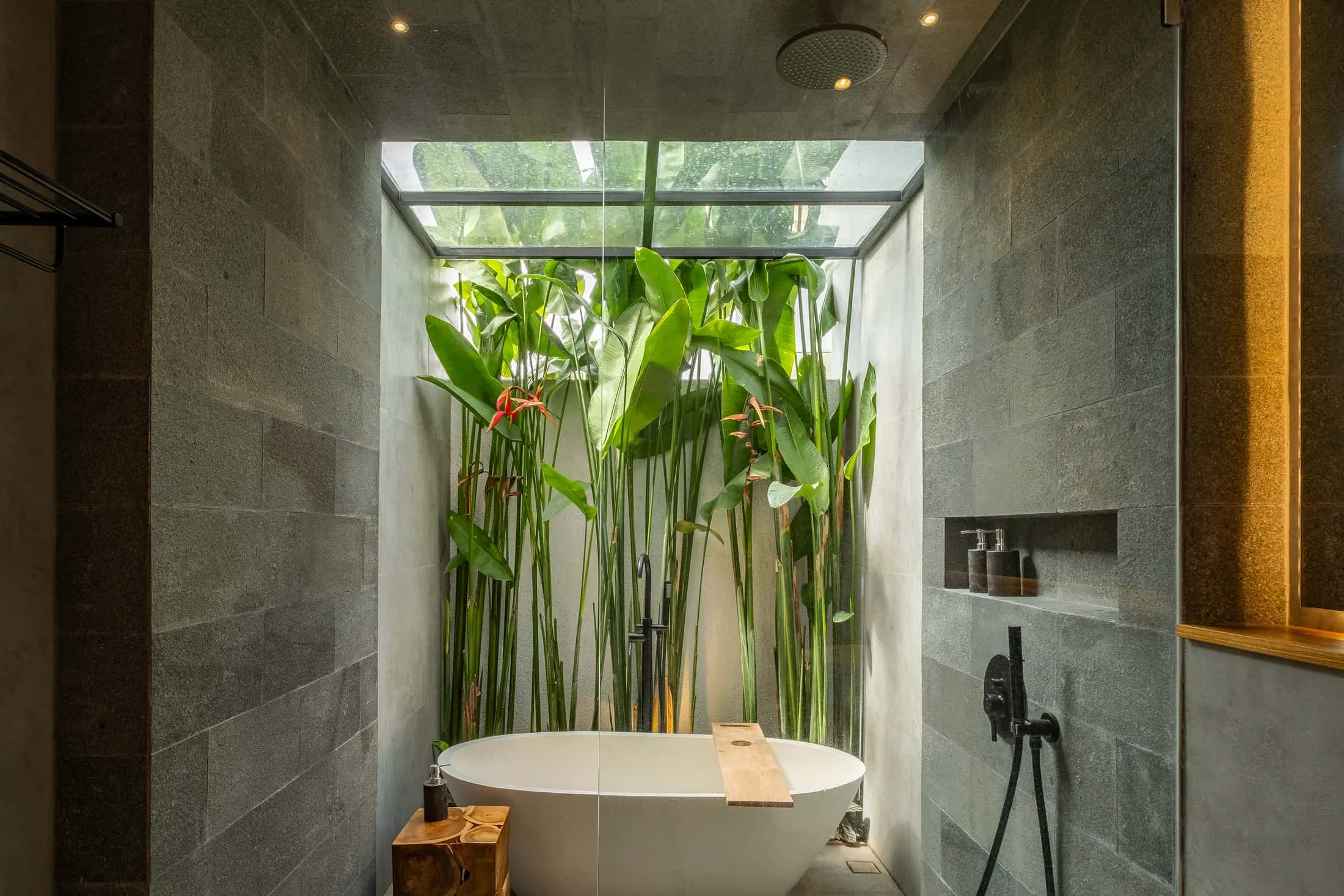 Mezzanine villa freestanding bathtub beneath a skylight with tropical plants