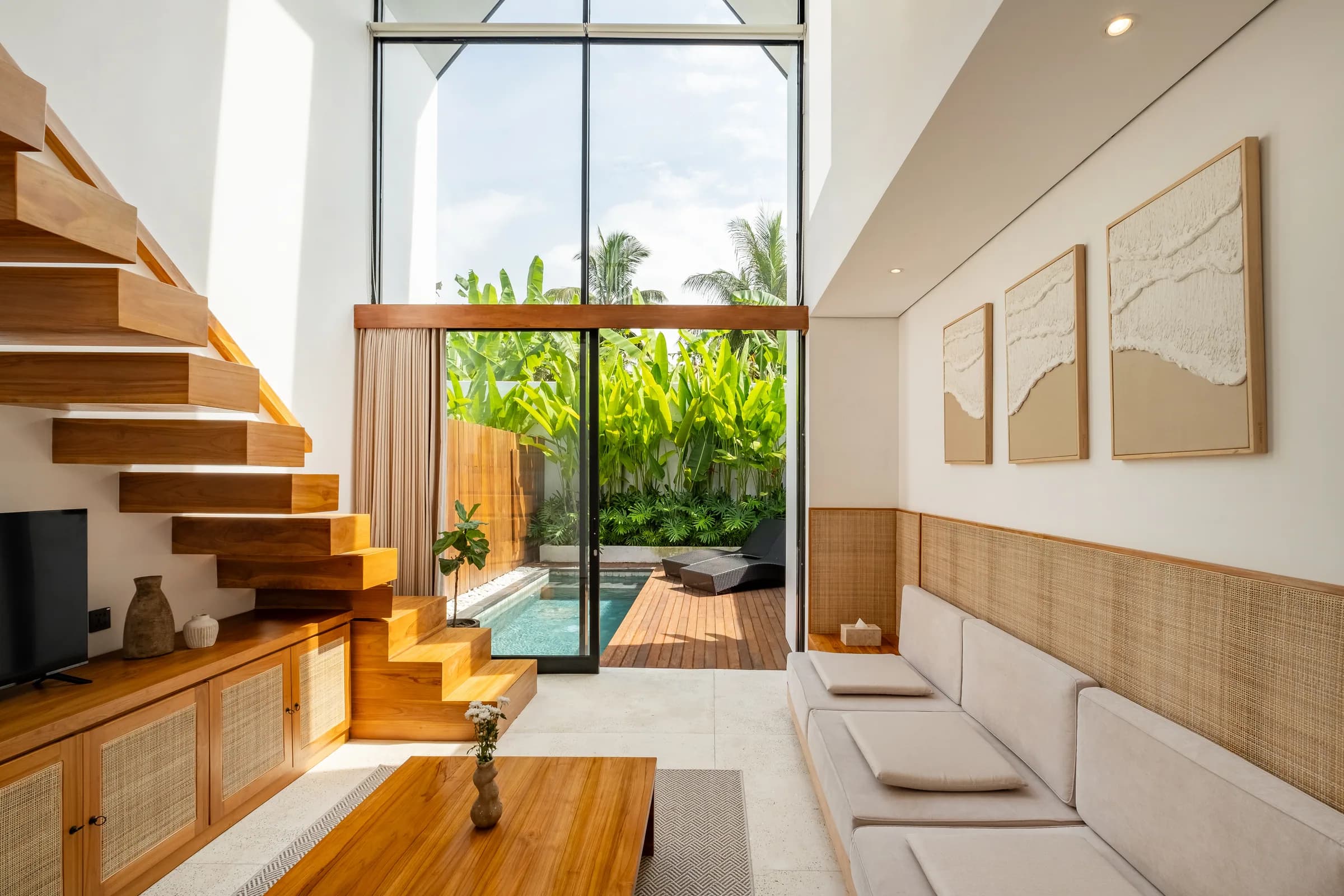 Mezzanine villa living room with floating staircase and private pool beyond
