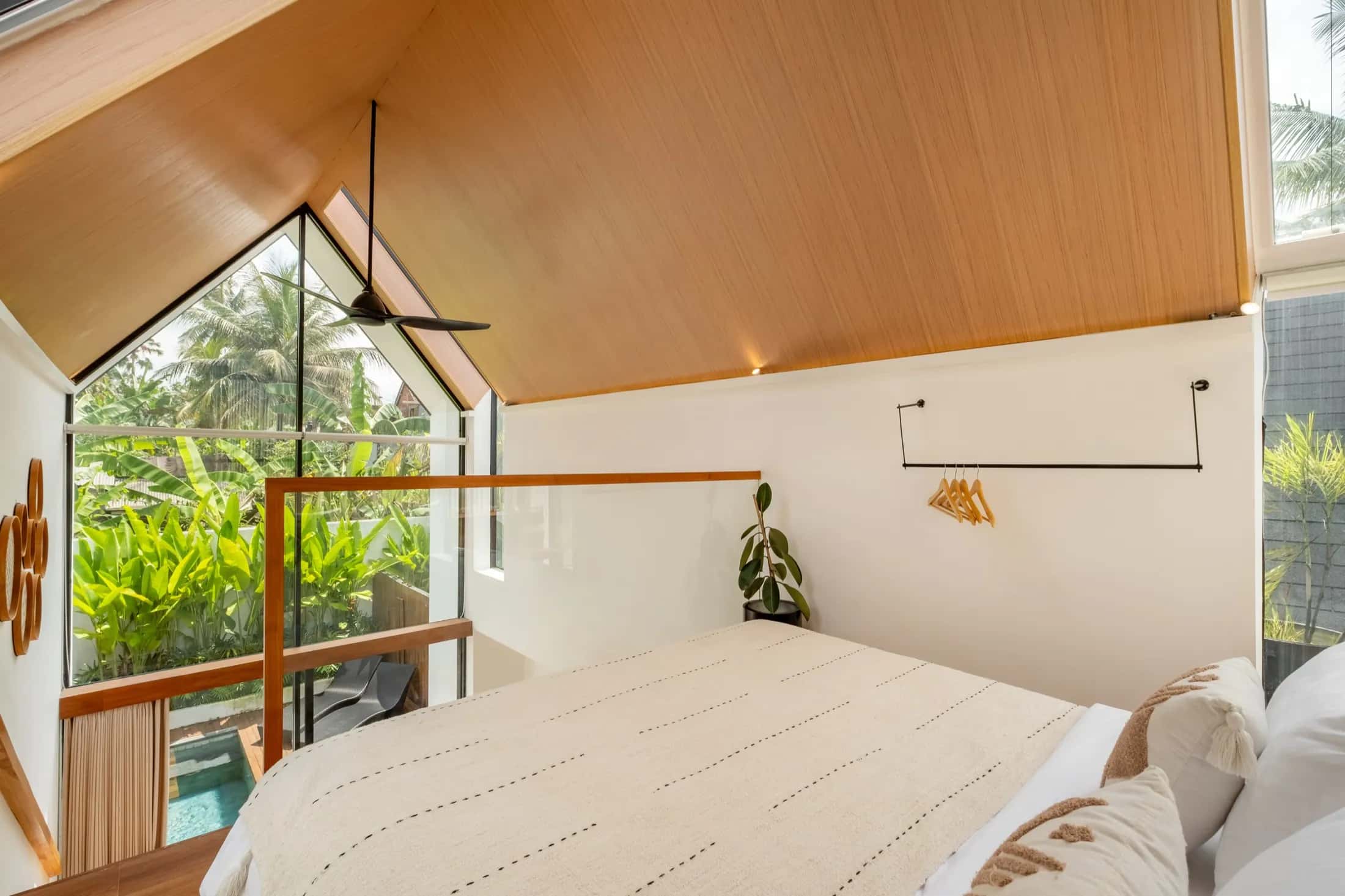Mezzanine villa upstairs bedroom with A-frame glass facade and pool view below