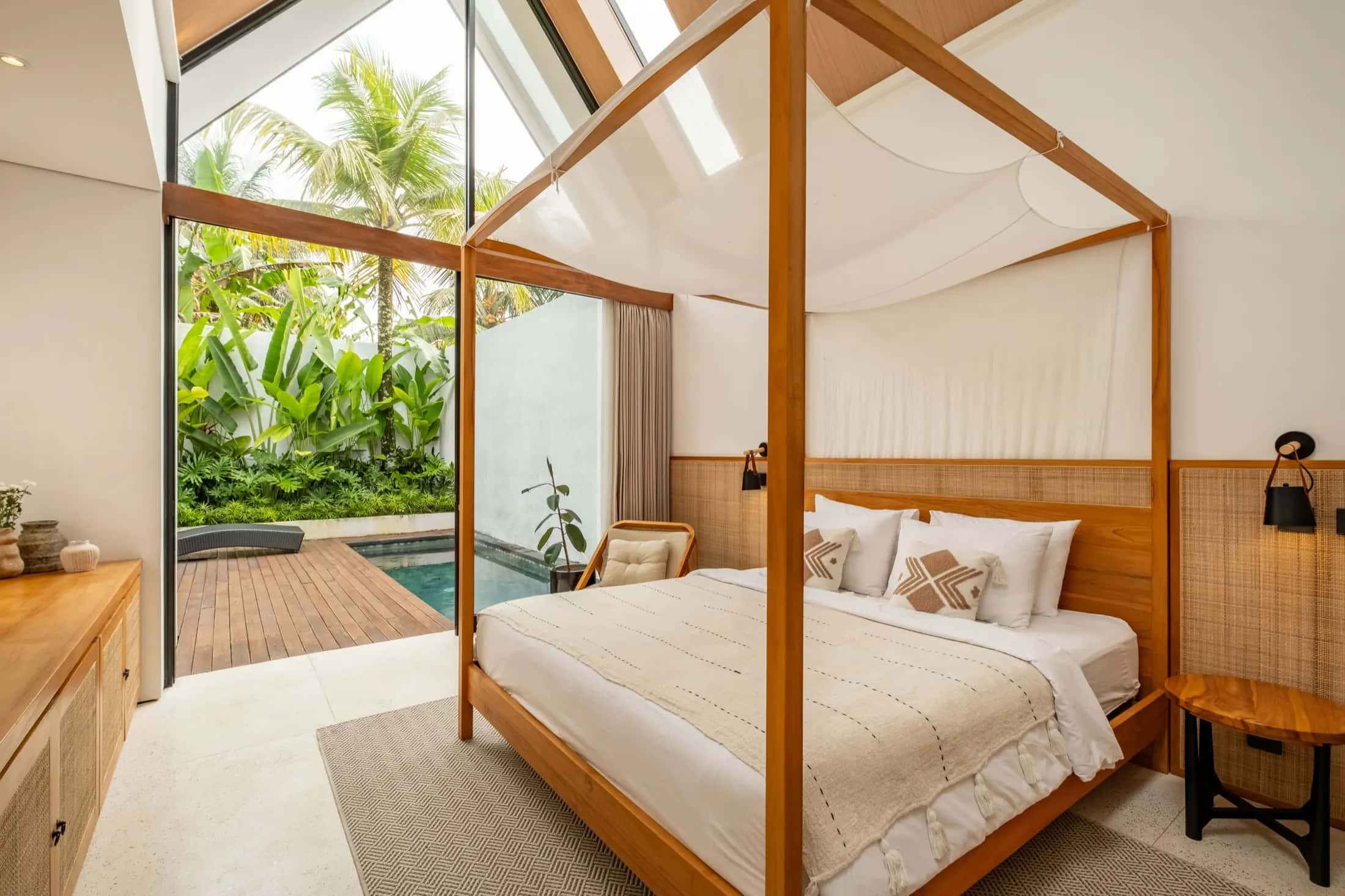 One Bedroom villa bedroom with four-poster bed and open glass doors to the private pool and tropical garden