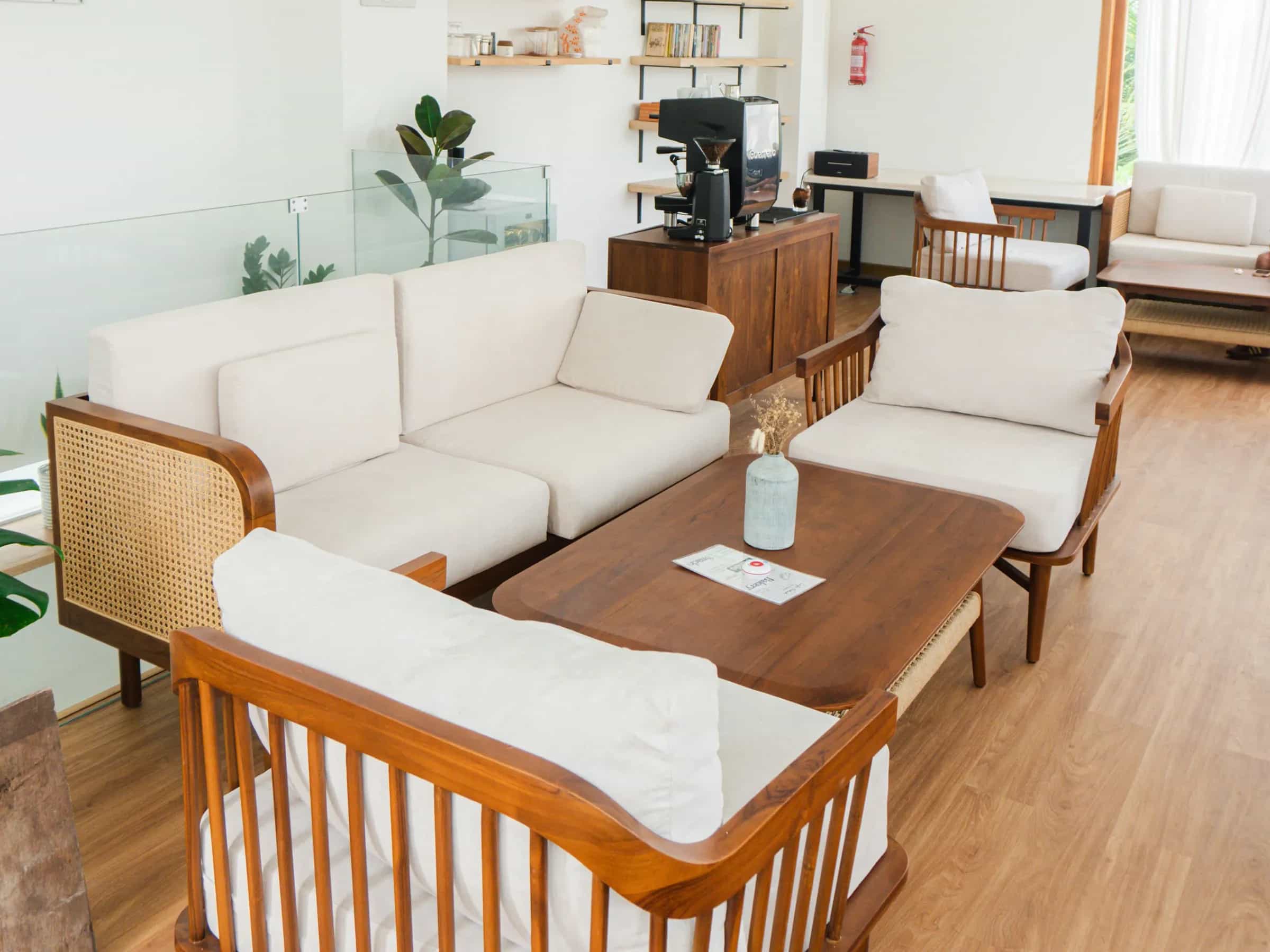 Cafe Teduh's lounge: teak and rattan sofas with cream cushions around a low table, and the coffee bar behind