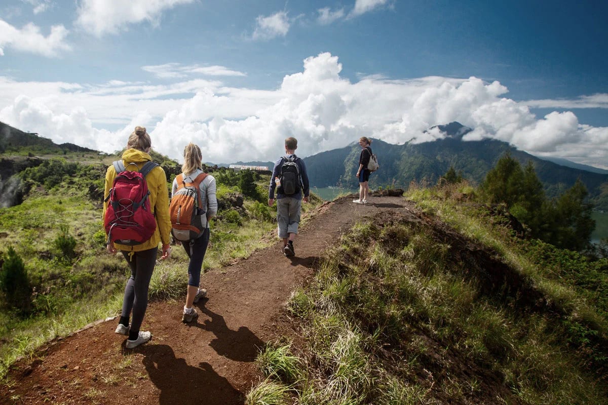 Group of trekkers hiking the red-earth ridge trail on Mount Batur under a blue sky